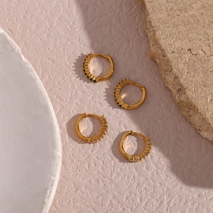 Close-up of small 18K gold-plated earrings with micro-set green and white zircons