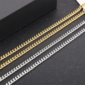 Detailed view of silver and gold stainless steel Cuban link chains on a black jewelry box