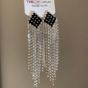 Detail of silver needle geometric diamond tassel earrings with sparkling rhinestones