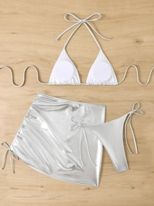 Flat lay of a white bikini top and metallic silver three-piece swimsuit with matching skirt
