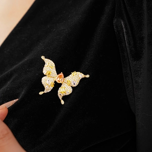 Detail of gold butterfly brooch with zircon stones and orange teardrop center stone