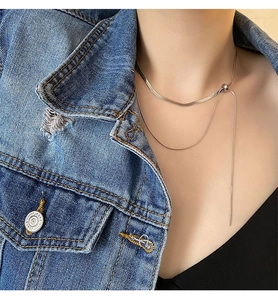 Close-up of layered silver snake chain and bead necklace on model with denim jacket