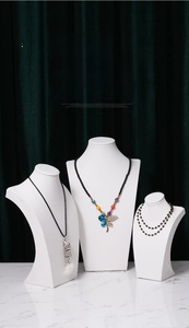 Three-piece set of white matte necklace bust displays on marble surface for jewelry store
