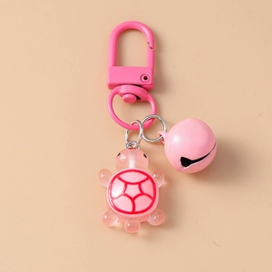 Detail of pink resin turtle keychain with a matching metal bell and golden clasp hook