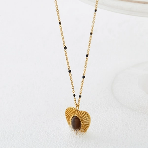 Collier cœur vintage doré avec pierre œil de tigre et perles noires sur fond blanc
