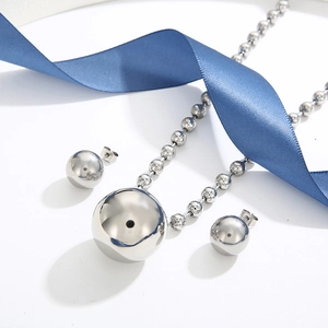 Detail of silver spherical jewelry set with ball chain necklace and stud earrings on ribbon