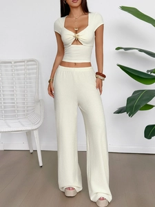 Detail of elegant beige knit two-piece set with golden starfish decor and cutout design
