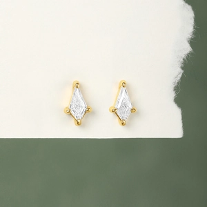 Macro view of gold-plated S925 silver stud earrings with zircon stones on white paper