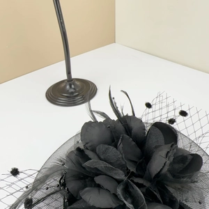 Close-up of vintage black fascinator with layered petals, feathers and polka dot mesh veil