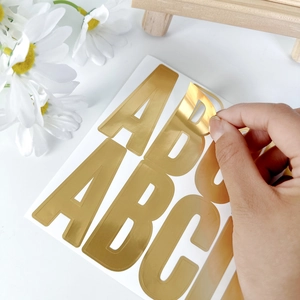Detailed view of 2.5-inch gold foil alphabet stickers on white surface with decor