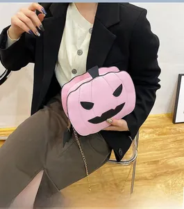 Detailed view of pink pumpkin cross-body bag with gold chain and bat pendant charm
