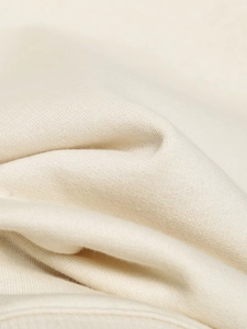 Detailed macro view of the soft beige knitted fabric texture and premium vertical drape