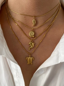 Close-up of gold layered necklace set featuring sea turtle, dolphin and conch pendants
