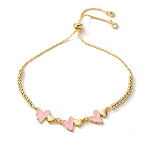 Bracciale a sfere dorato regolabile con ciondoli a cuore in smalto rosa su fondo bianco