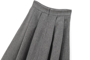 Detail of grey herringbone pleated skirt showing waist stitching and hidden zipper