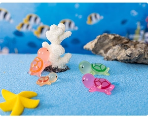 Luminous resin turtle figurines in multiple colors set against a blue sand seabed scene