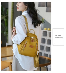 Woman wearing mustard yellow nylon mini backpack with adjustable logo straps