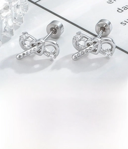 Detailed specs of bow-tie cartilage stud earrings with heart infinity design and zircon