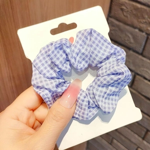 Close-up of a purple and white checkered scrunchie on a white retail card display