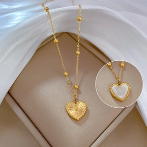 Macro detail of a double-sided heart pendant with gold texture and white mother of pearl