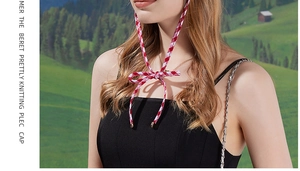 Detail of red and white plaid straps tied in a bow on a stylish knitted beret cap