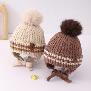 Detail of knit baby hats with pom-poms, ribbed edges and leather Kuki brand labels