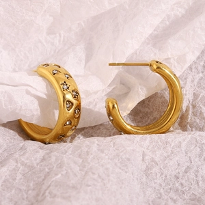 Macro shot of 18K gold plated C-shaped earrings with embossed stars and zircon center