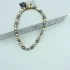 Close-up of mixed pearl necklace with silver moon clasp on a white book surface