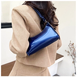 Rear view of model wearing a glossy dark blue patent leather shoulder baguette bag