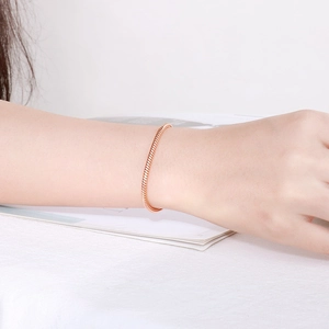 Detailed view of a rose gold stainless steel snake chain bracelet on a woman's wrist