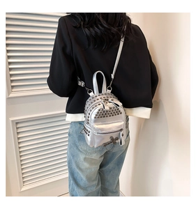 Detail of silver mini backpack with punk studs and cross chain charm on model back
