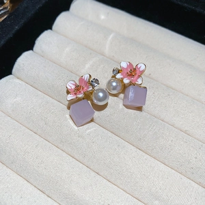 Close-up of pink cherry blossom earrings with a pearl and purple cube pendant
