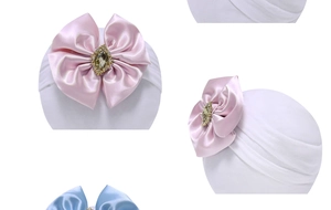 Detail of white nylon baby headband with a satin bow and sparkling rhinestone centerpiece