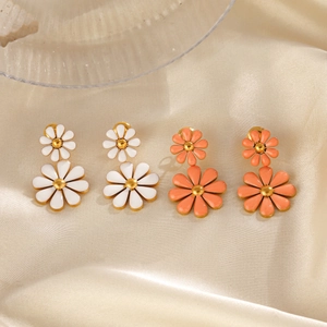 Double-layered daisy drop earrings in white and coral orange enamel on silk background