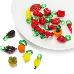 Close-up of colorful glass fruit and vegetable charms on a white ceramic plate