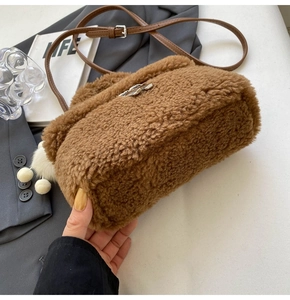Detail of brown plush small square bag with leather strap and silver metal buckle closure