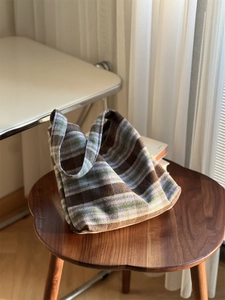 Sac cabas vintage en laine à carreaux bleus et marrons sur un tabouret en bois