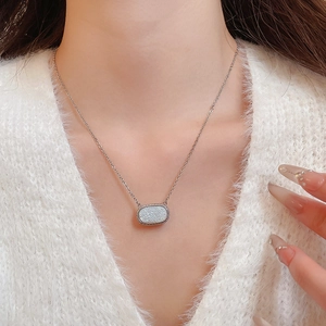 Close-up of minimalist resin oval pendant necklace on a soft white sweater background