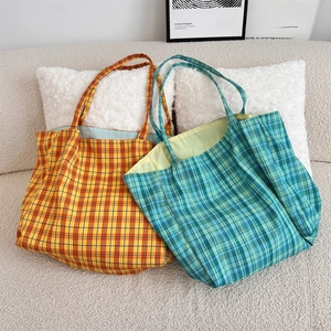Detail of checkered canvas tote bags in yellow and green resting on a white sofa