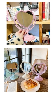 Detailed view of vintage heart-shaped desktop makeup mirrors in pink, blue, and cream colors