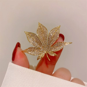 Detailed macro shot of a golden maple leaf brooch with sparkling pavé-set zircon crystals