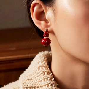 Detail of red gourd earring with gold plating and crystal accents worn by a model