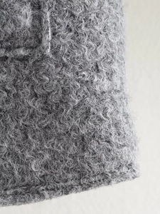 Gros plan sur la texture bouclée en laine grise d'un manteau court pour femmes