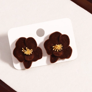 Close-up of deep brown velvet flower earrings with golden core on white card