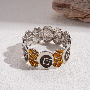 Detail of elastic bracelet with tiger-stripe enamel, silver stars and rhinestones