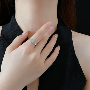 Detail of silver gourd ring with light green jade stone and sparkling crystals on finger