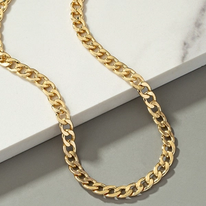 Hip hop style gold Cuban link necklace displayed on white marble and grey background