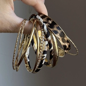 Close-up of leopard print and gold metal bangles with rhinestone inlay and fabric details