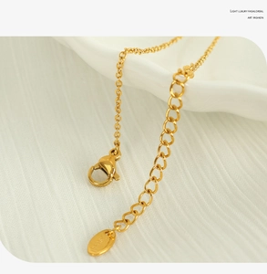 Close-up of golden stainless steel necklace lobster clasp and extension chain on white fabric