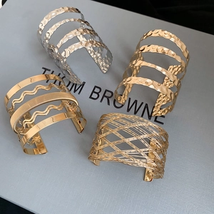 Macro detail of wide textured bangles with layered metallic ripples and mesh patterns